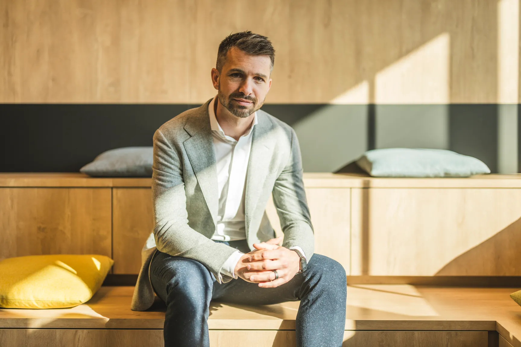 Een transfer pricing expert die op een bank zit en in de lens kijkt.