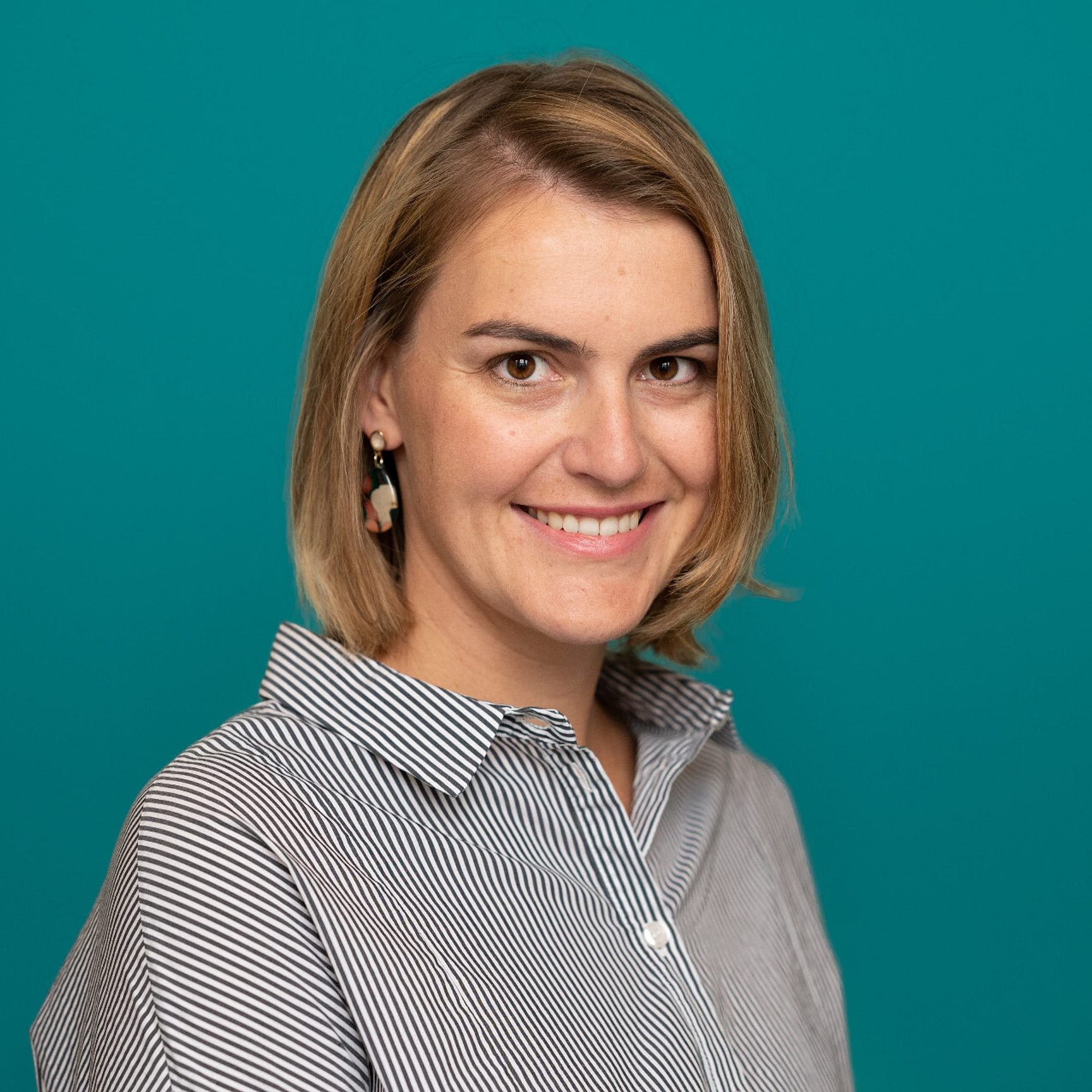 Een profielfoto van een vrouw met een appelblauwzeegroene achtergrond.