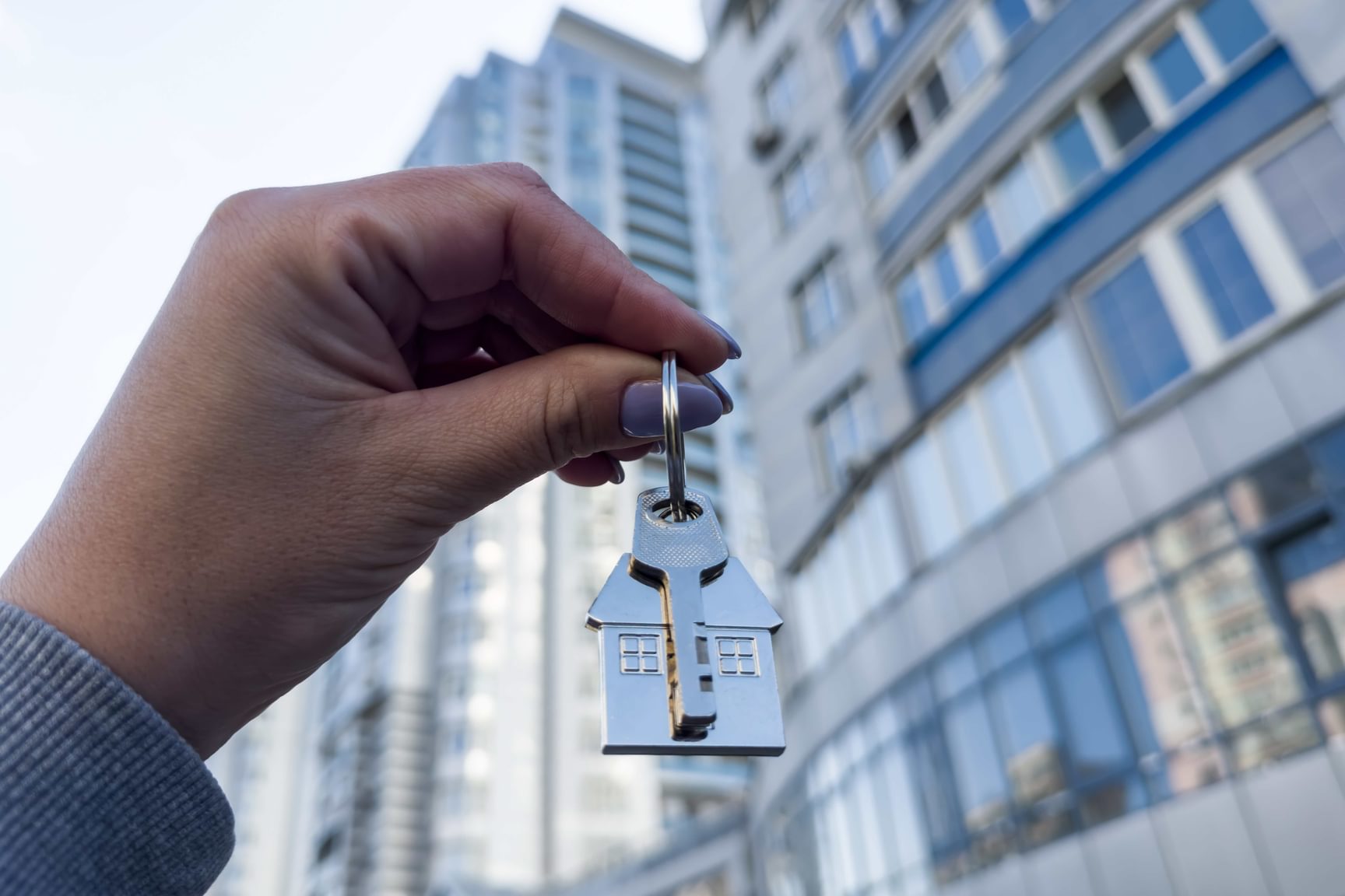 Hand houdt een huissleutel vast voor een appartementsgebouw bij bedrijfsovername