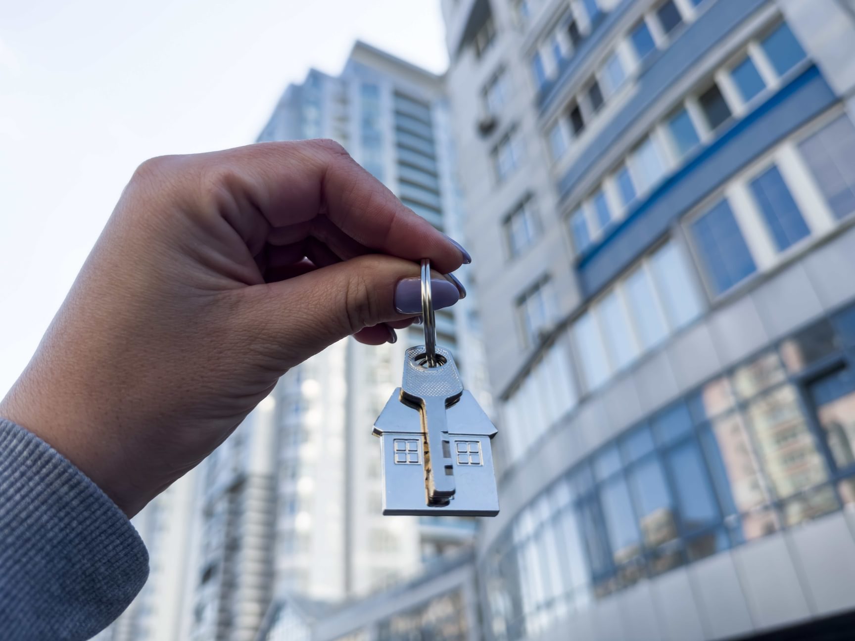 Hand houdt een huissleutel vast voor een appartementsgebouw bij bedrijfsovername