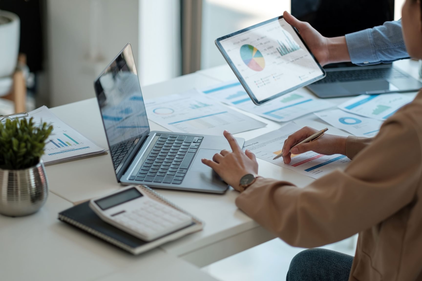 Foto van iemand die financiële cijfers analyseert op een laptop en tablet, als symbool voor fiscale optimalisatie en geld uit een vennootschp halen.