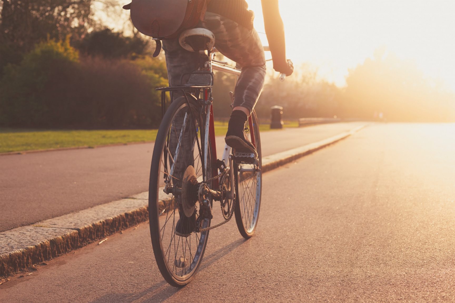 Persoon fietst op een weg bij zonsondergang met een rugzak op de rug.