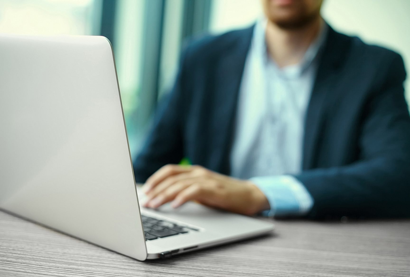 Persoon werkt op een laptop aan een bureau in een kantooromgeving.