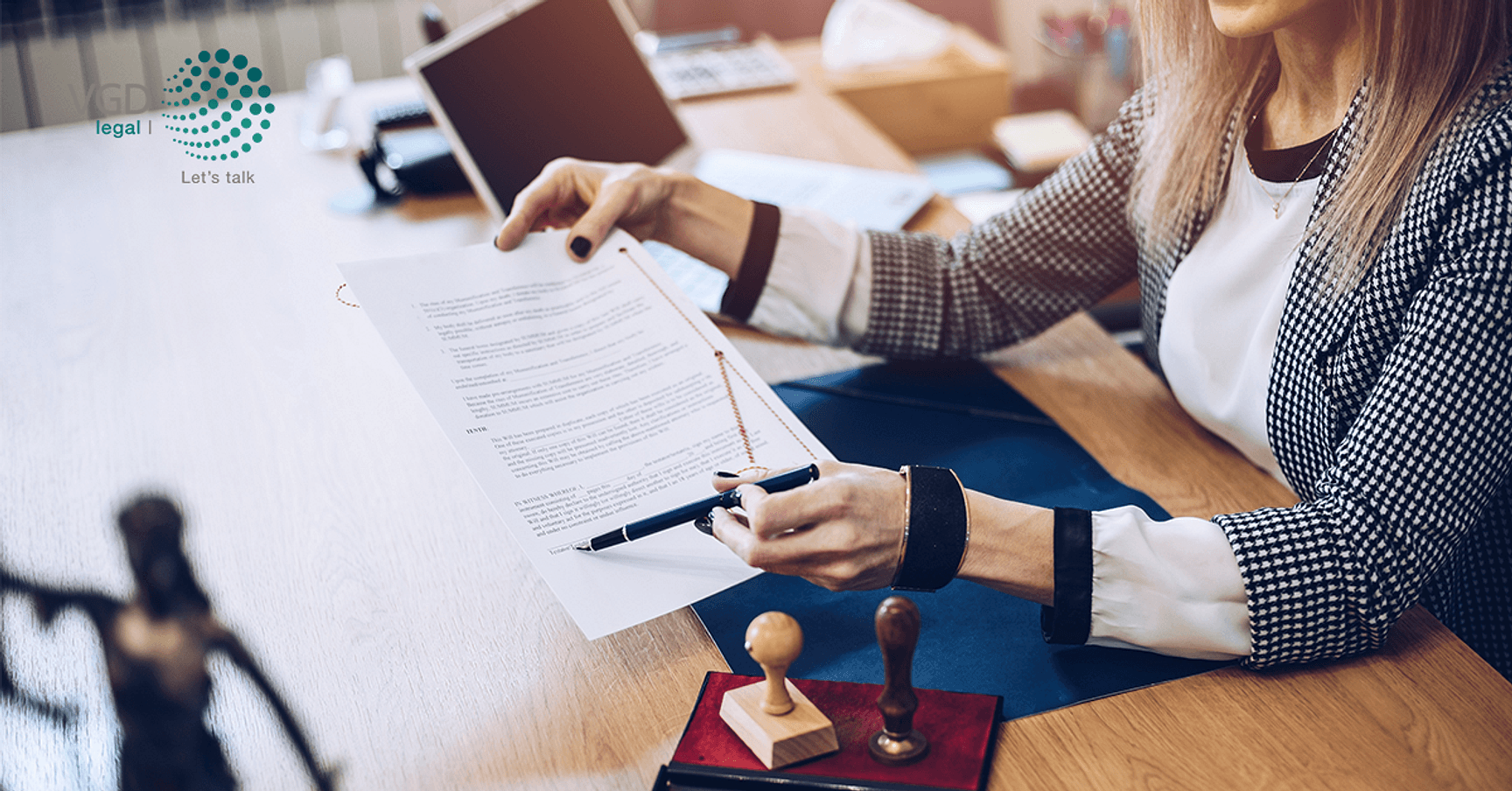 Persoon houdt een document vast en wijst met een pen naar de inhoud aan een bureau.
