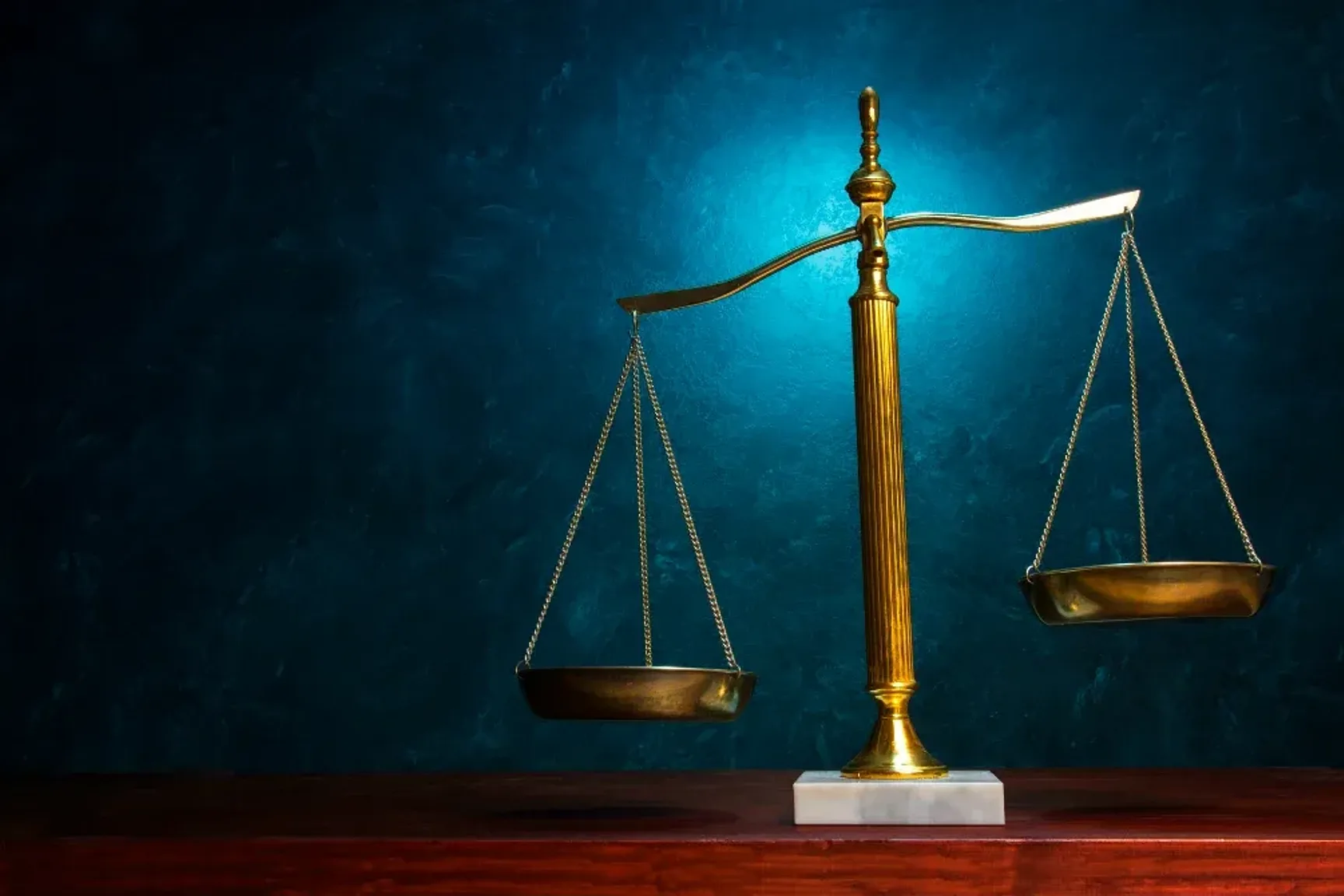 Gouden weegschaal op een houten tafel tegen een blauwe achtergrond.