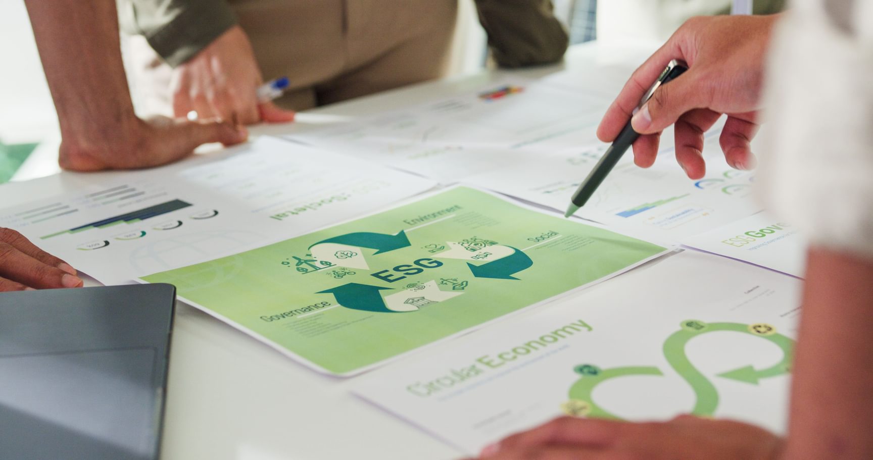 Een aantal mensen dat rond een tafel staan met daarop strategische documenten omtrent ESG.