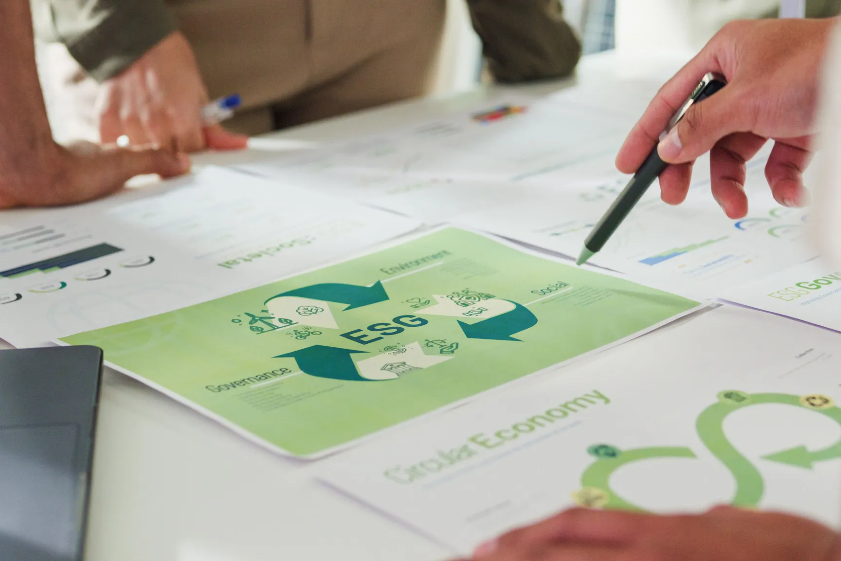 Een aantal mensen dat rond een tafel staan met daarop strategische documenten omtrent ESG.