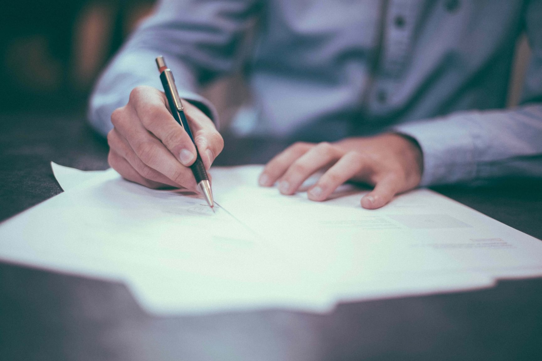 Close-up van een VGD-medewerker die een contract of document tekent met een balpen.