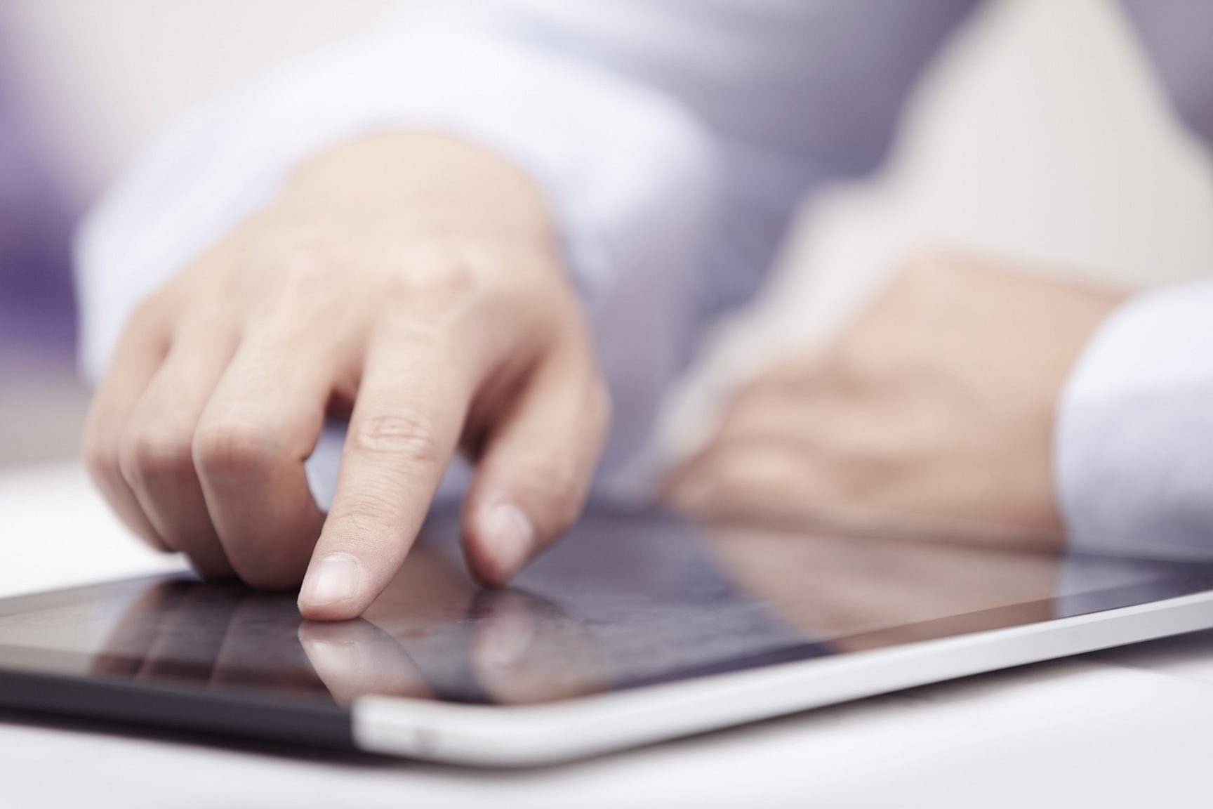Hand die op een tablet tikt dat op een bureau ligt.