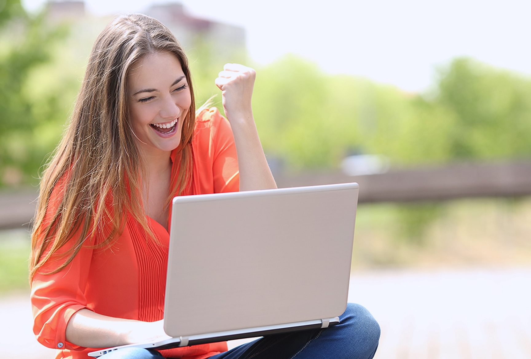 Persoon zit buiten te werken achter haar laptop.