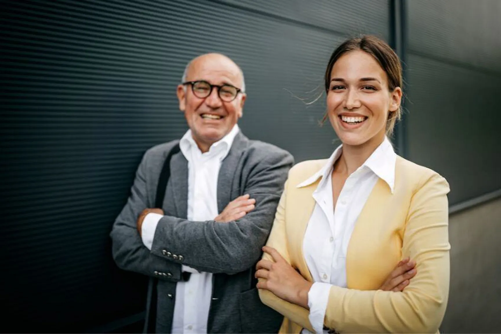 Foto van twee ondernemers voor een bedrijfspand, als beeld van familiale overdracht en het schenken van een vennootschap aan 0%.