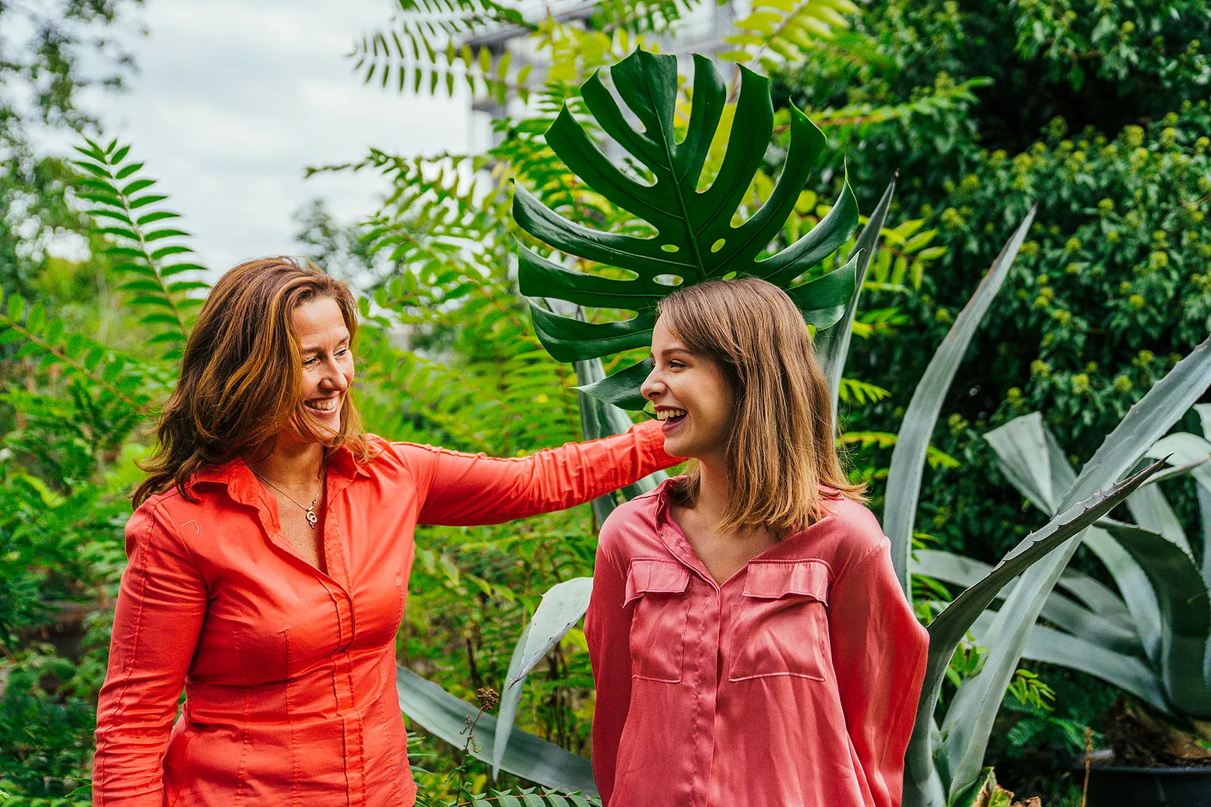 Twee lachende collega's zijn aan het wandelen. De  dame links gooit blij een arm rond de schouder van haar jongere collega rechts. De foto straalt warmte, collegialiteit en samenwerken uit.