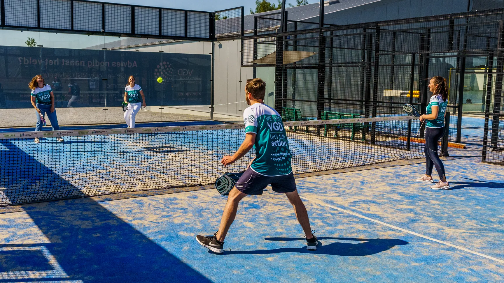 Vier collega's staan in VGD tenue te paddelen. Je ziet hen in volle actie lopen naar de bal.