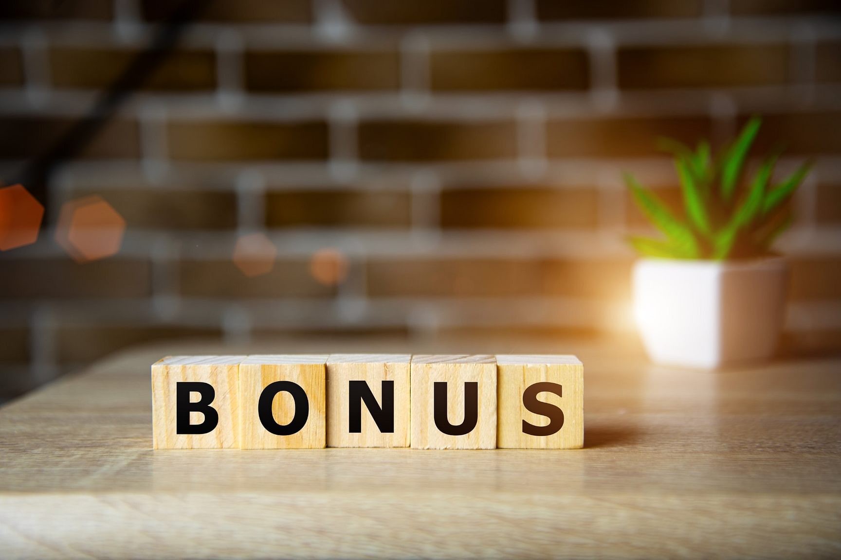 Een aantal houten blokken met daarop de letter: b,o,n,u & s. Die het woord bonus spellen.